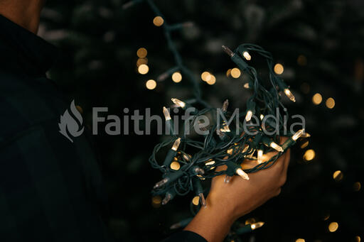 Man Putting Twinkle Lights on a Christmas Tree