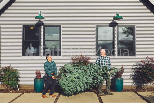 Two Men Carrying a Christmas Tree into a House