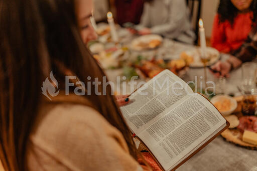 Woman Reading from the Bible before Thanksgiving Dinner
