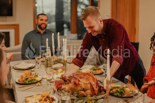 Man Placing the Thanksgiving Turkey on the Dinner Table