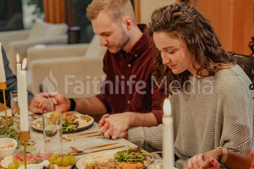 Friends Praying Before Thanksgiving Dinner