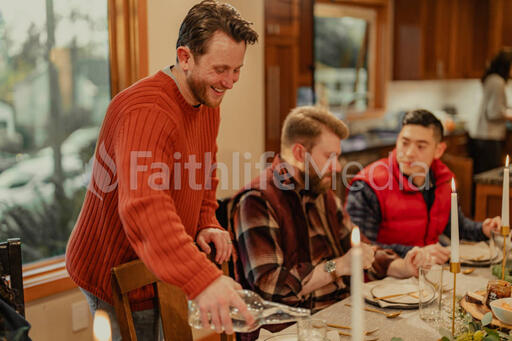 Man Pouring Water for People at the Dining Table