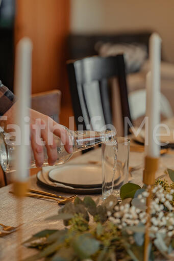 Man Pouring Water into Glasses at Thanksgiving Table