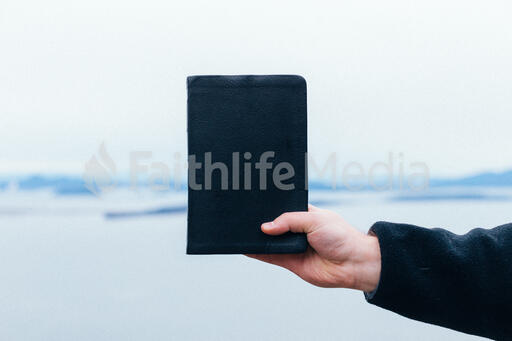 Man Holding a Bible Up in the Air