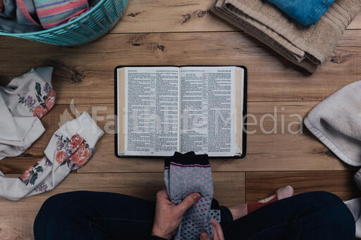 Woman Reading the Bible while Folding Laundry