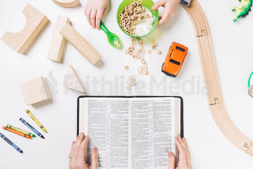 Mom Reading the Bible While Her Child Spills His Cereal